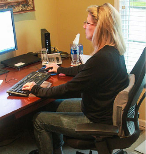 Woman in home office chair using lumbar support pillow